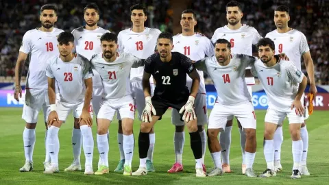 Iranska nogometna reprezentacija u bijelim dresovima pozira na terenu.