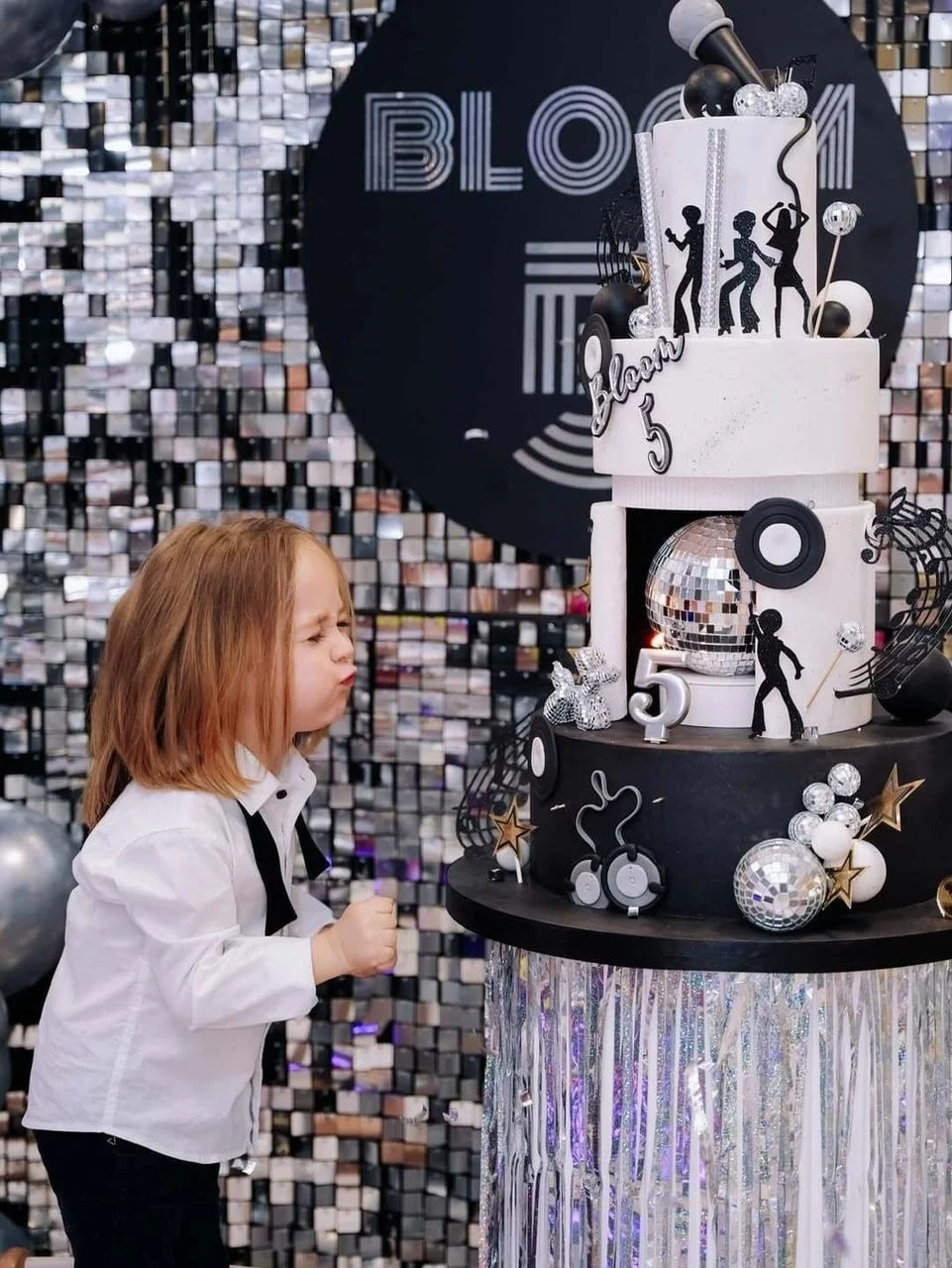 Dječak Bloom puše u svjećicu na velikoj rođendanskoj torti s disko motivima.