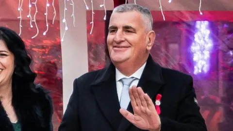 Miro Bulj u tamnom kaputu sa smiješkom maše rukom u svečanoj prigodi.