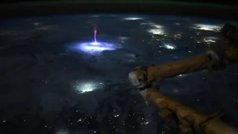 Plavi mlaz i crveni sprite bljesak iznad olujnih oblaka snimljeni iz svemira.