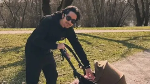 Igor Drvenkar u crnoj sportskoj odjeći šeće kćer u dječjim kolicima po sunčanom vremenu.