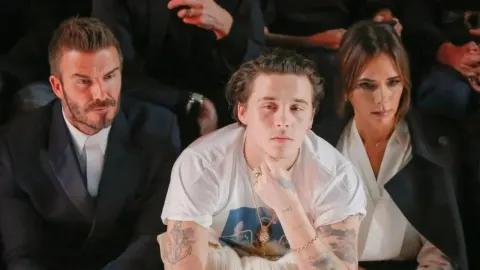 David, Brooklyn i Victoria Beckham sjede zajedno na modnom događaju.