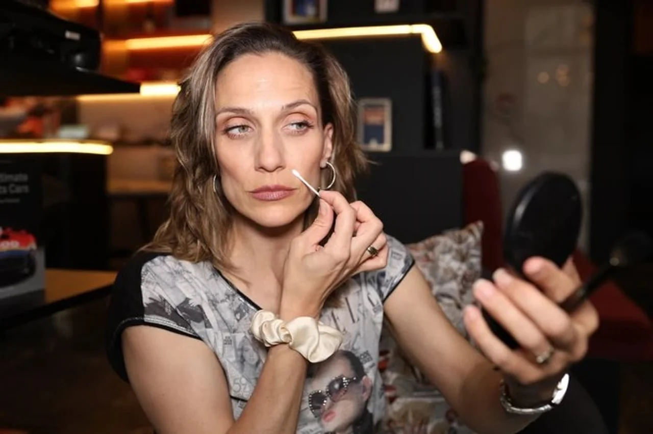 Žena nanosi korektor na usne pomoću štapića gledajući u ogledalce