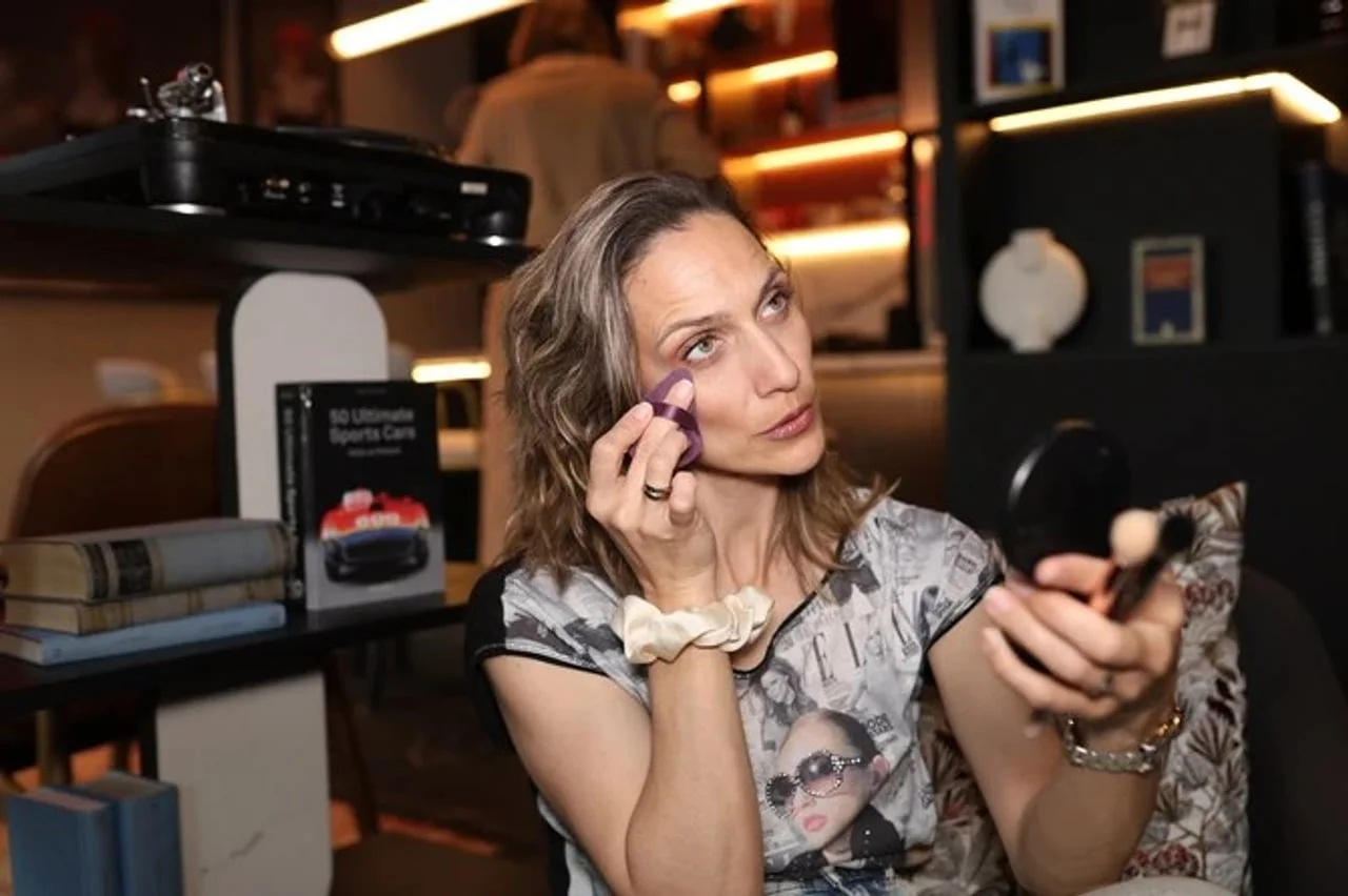 Žena koristi ljubičasti beauty blender za blendanje šminke na licu