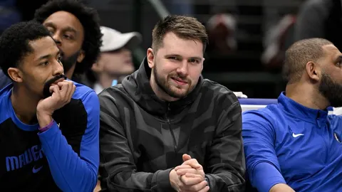 Košarkaš Luka Dončić u sivoj zimskoj jakni sjedi na klupi