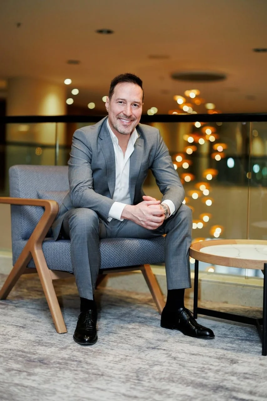 Peđa Jovanović sjedi u sivom odijelu u moderno uređenom interijeru.