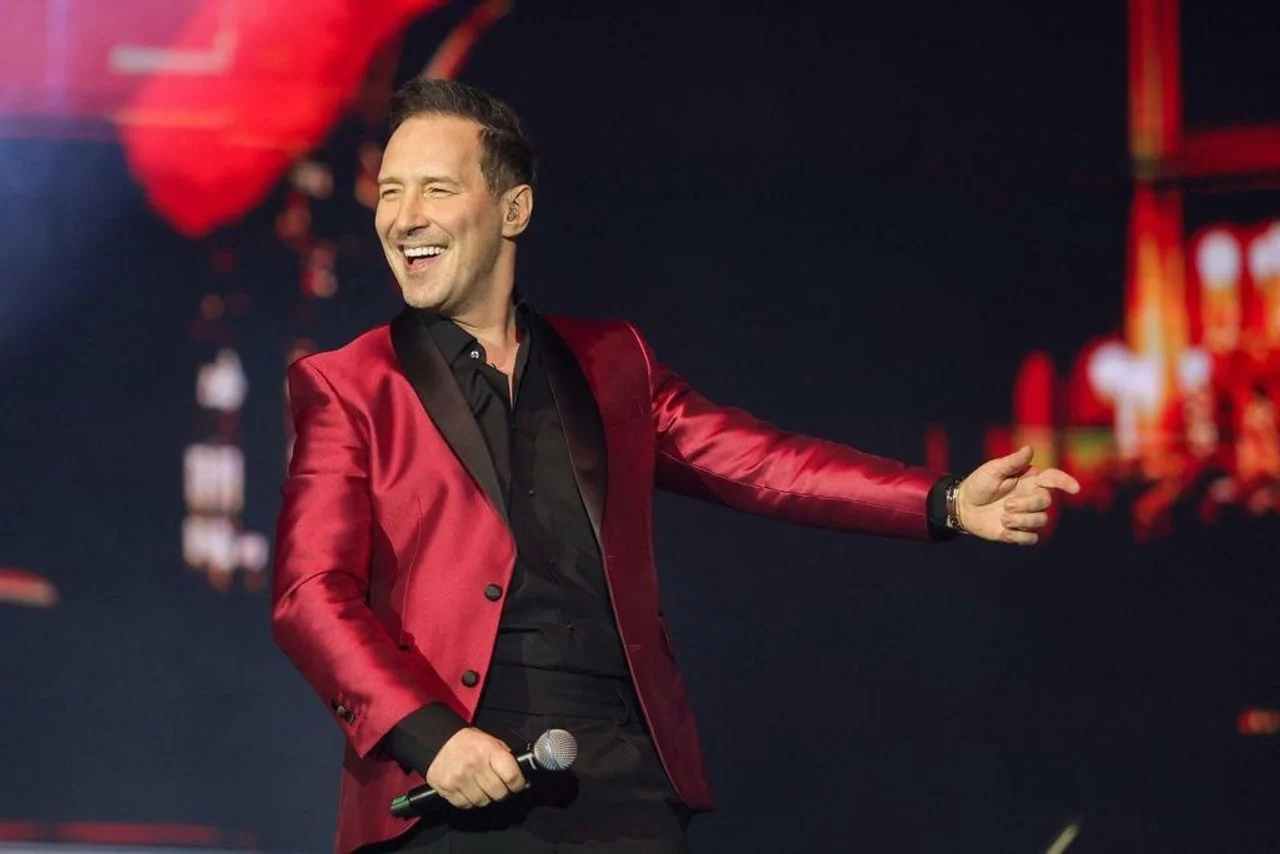 Peđa Jovanović pjeva na pozornici u crvenom sjajnom sakou.