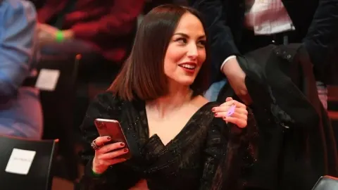 Nasmiješena Tatjana Jurić s pametnim telefonom u rukama na javnom događanju.