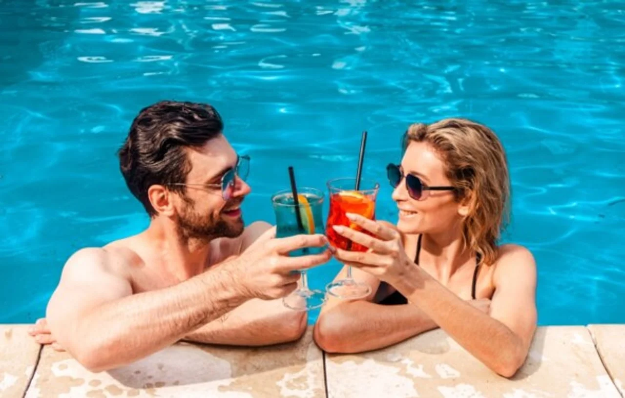 Muškarac i žena s okularima za sunce piju koktele u bazenu