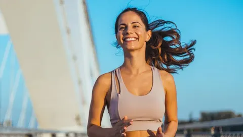 Nasmijana žena u sportskoj odjeći trči na otvorenom