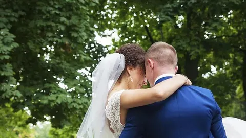 Mladi bračni par u zagrljaju na otvorenom prostoru s drvećem u pozadini