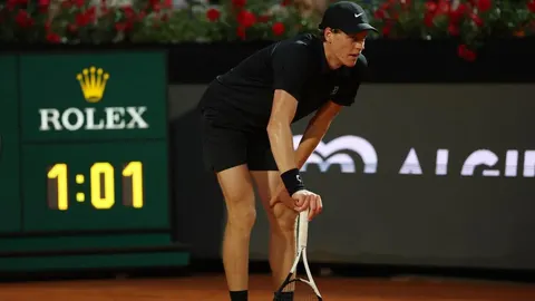 Tenisač Jannik Sinner u crnoj odjeći stoji nagnut na glinu