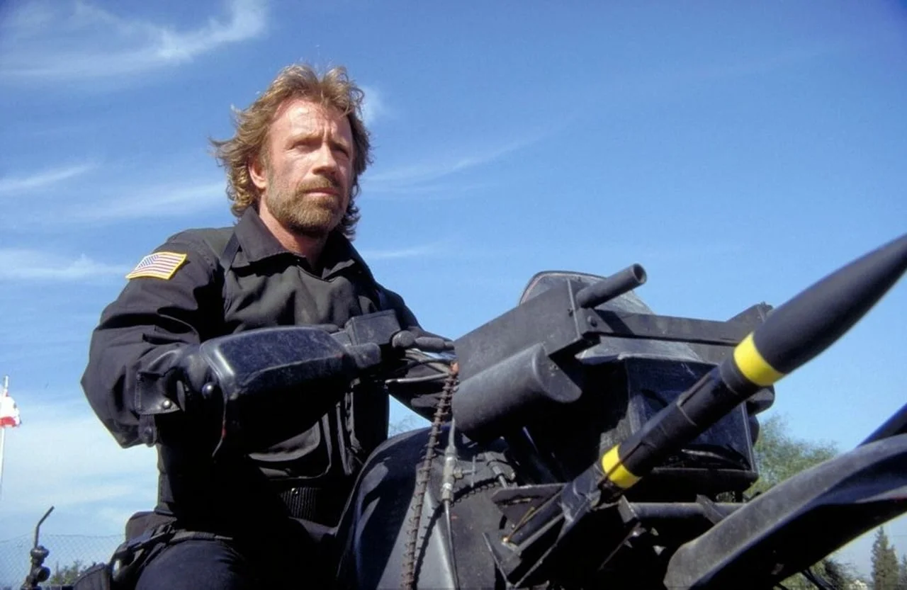 Chuck Norris na tamnom motociklu u crnoj uniformi s američkom zastavom