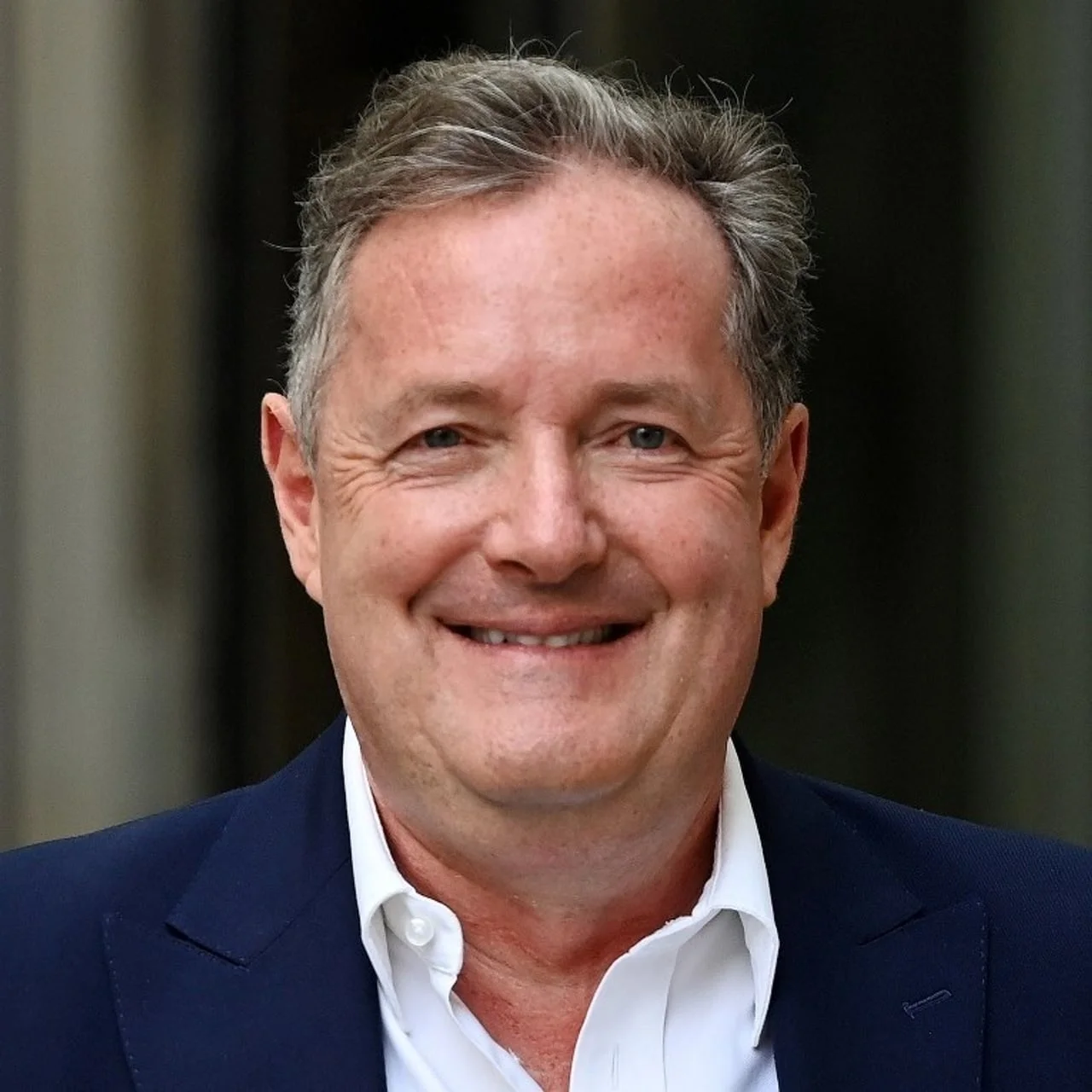 Portret poznatog televizijskog voditelja Piersa Morgana u tamnom odijelu i bijeloj košulji.