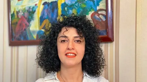 Portret žene s kovrčavom crnom kosom ispred apstraktne slike