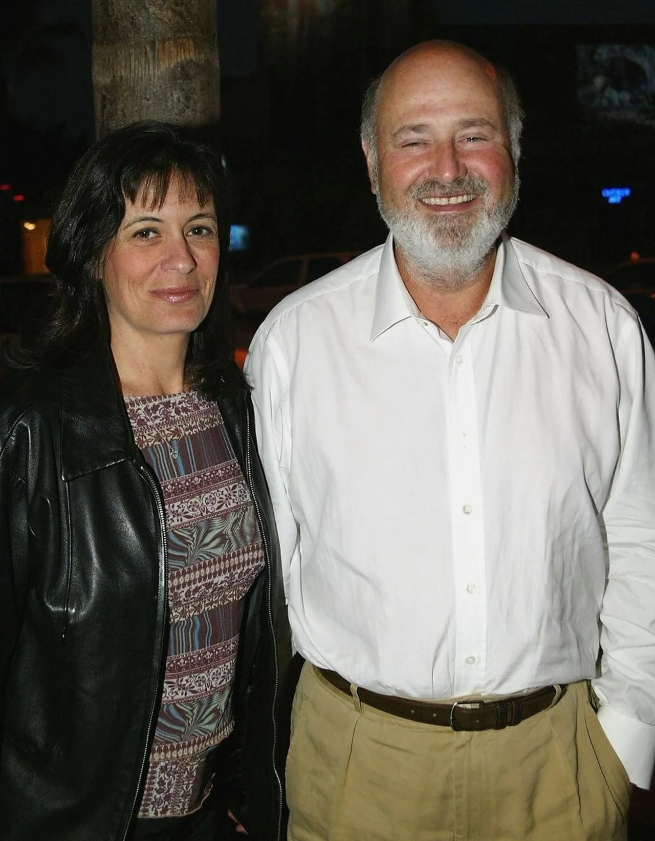 Rob Reiner u bijeloj košulji nasmijan pored supruge Michelle u kožnoj jakni.