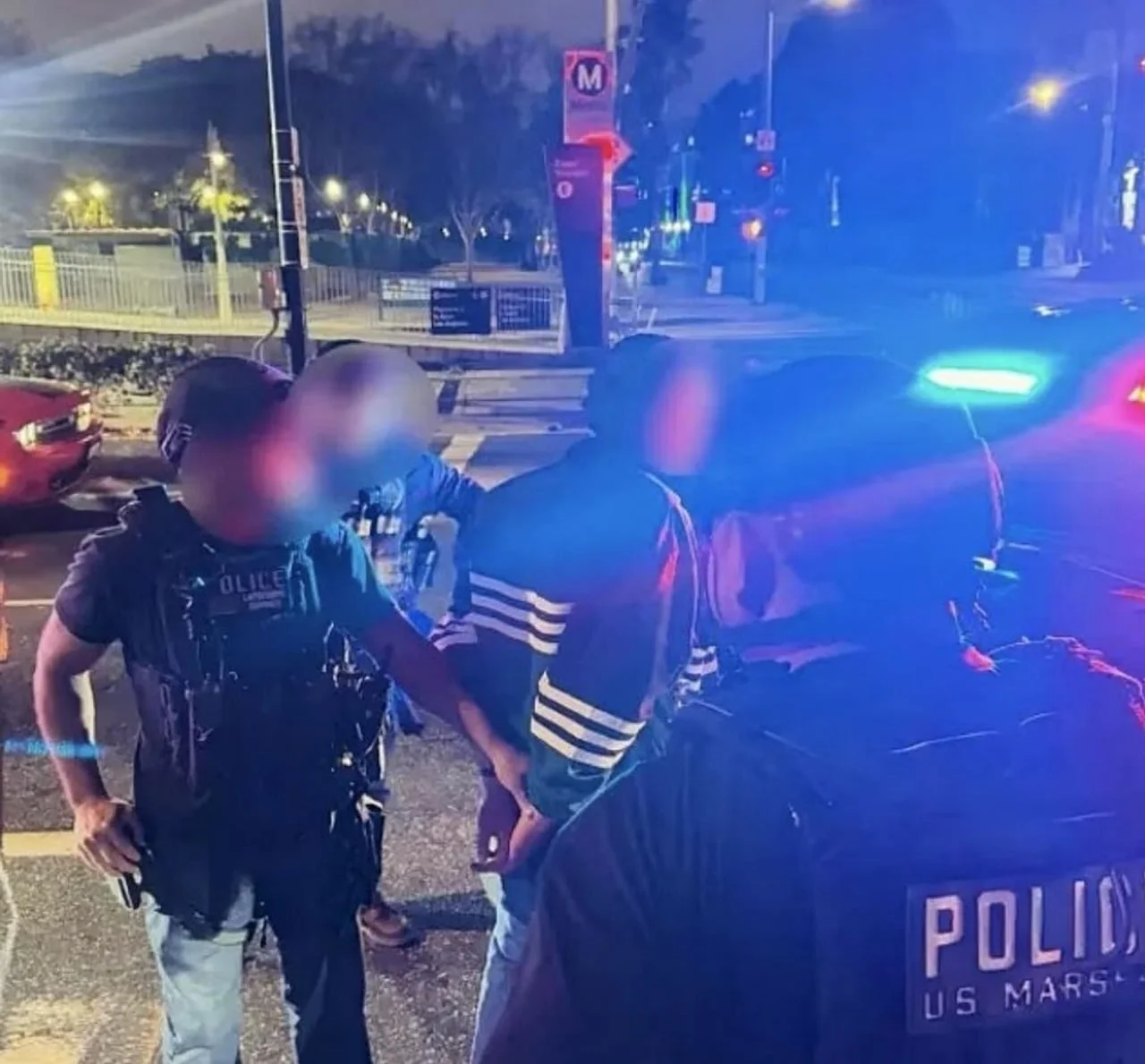 Policajci s natpisom US MARSHAL na leđima privode osobu s lisicama noću.