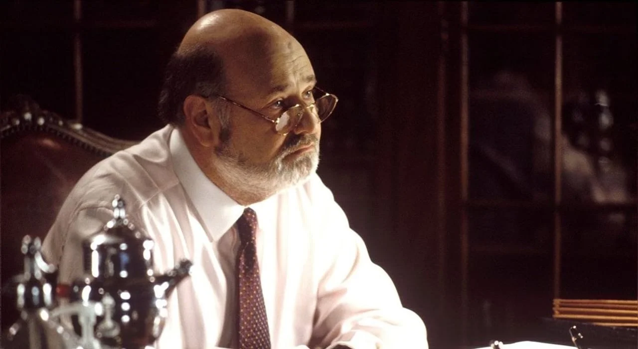 Rob Reiner s naočalama sjedi za stolom u radnoj sobi klasičnog stila.