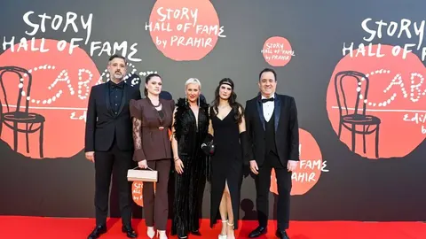 Grupa ljudi u svečanim odjećama pozira ispred Story Hall of Fame zida