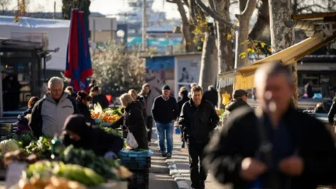 Ljudi koji kupuju povrće i voće na otvorenom gradskom tržnici