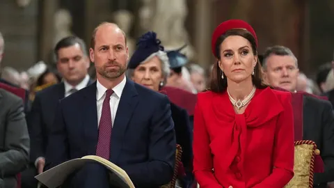 Princ William u tamnom odijelu i Kate u crvenom kostimu i šeširu
