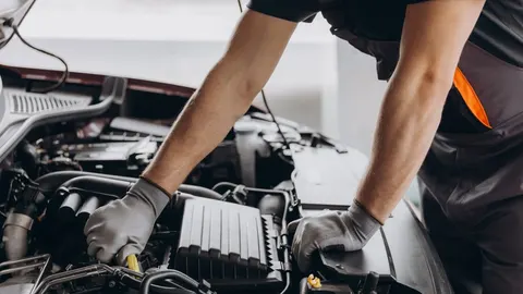 Mechaničar u rukavicama pregledava motor automobila u radionici