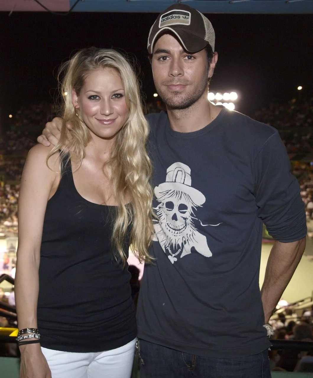 Enrique Iglesias s kapom i Anna Kournikova poziraju zagrljeni na događanju.
