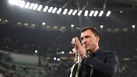 Mario Mandžukić u tamnom odjeću plješe ruke na nogotnom stadionu