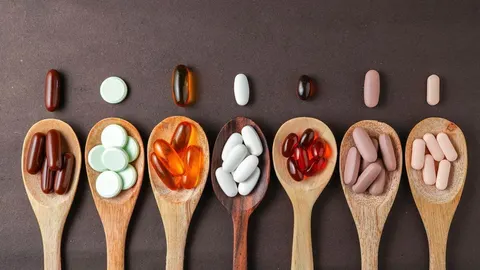 Različite vrste vitamina i minerala u obliku kapsula i tableta na drvenim žlicama