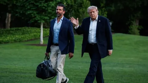 Donald Trump i njegov sin Donald mlađi šetaju travnjakom u odijelima