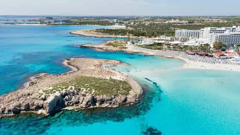 Zračni pogled na tirkizno more, pješčanu plažu i bijeli hotel na Cipru