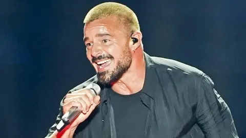 Ricky Martin s mikrofonom u ruci smiješi se tijekom nastupa na koncertu