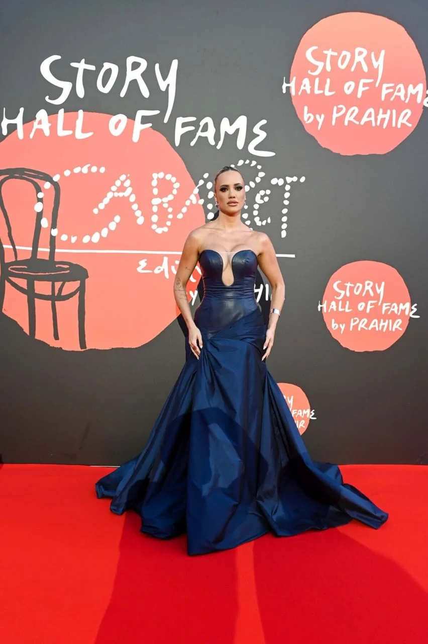 Žena u elegantnoj tamnoplavoj dugoj haljini na crvenom tepihu