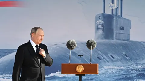 Vladimir Putin u crnom odelu za govornikom ispred ruske podmornice