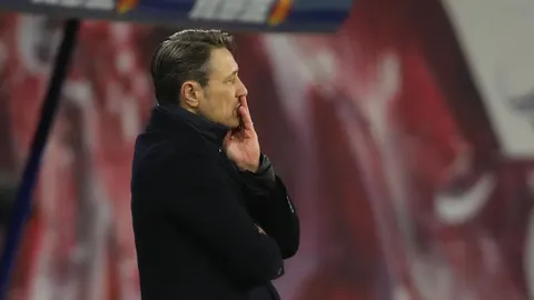 Profil Niko Kovača u crnom kaputu, razmišlja na rubu terena
