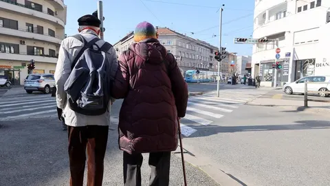 Stariji bračni par s leđa stoji na ulici pored pješačkog prelaza