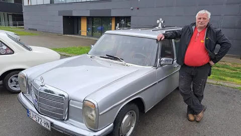 Srebrni vintage Mercedes 115 s osobom pored automobila