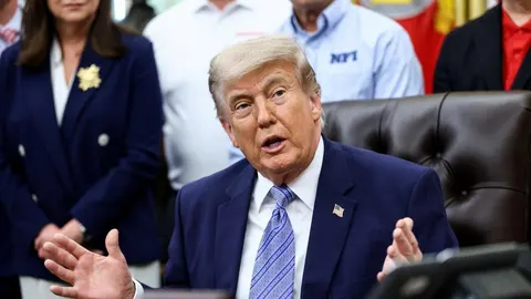 Donald Trump u plavom odelu i plavoj kravati govori s raširenim rukama