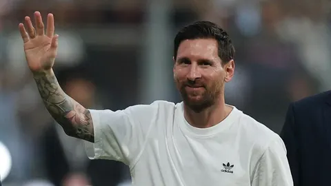 Lionel Messi u bijeloj majici maše rukom gledateljima na stadionu