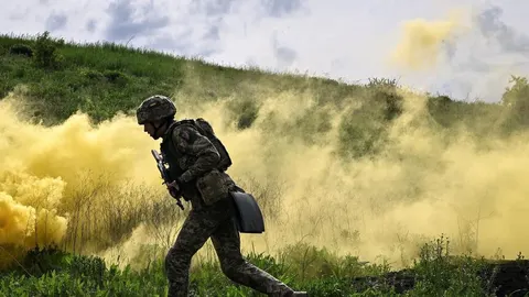 Vojnik u punoj opremi hoda kroz gusti žuti dim na zelenom terenu