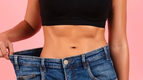 Žena drži preširoke traperice oko struka na pink pozadini