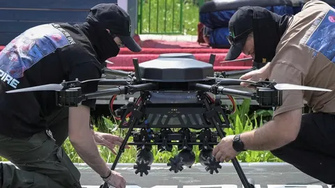 Dva muškarca u crnim kapama pripremaju veliki vojni dron