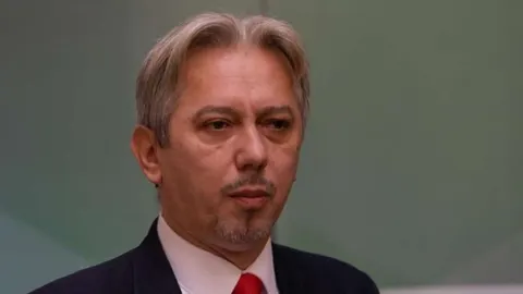 Portret Slalenaa Kovačevića u odijelu s crvenom kravatom