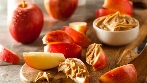 Narezane crvene jabuke s kremastim maslacem od kikirikija
