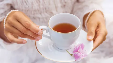 Ženske ruke koje drže bijelu šalicu s toplim oolong čajem
