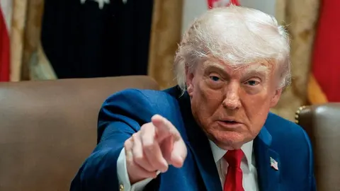 Donald Trump u plavom odelu i crvenoj kravati pokazuje prstom napred