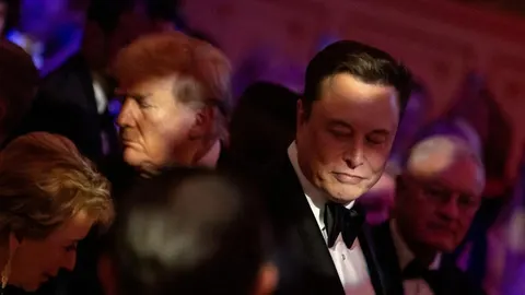 Elon Musk u crnom smokingu s Donaldom Trumpom u pozadini