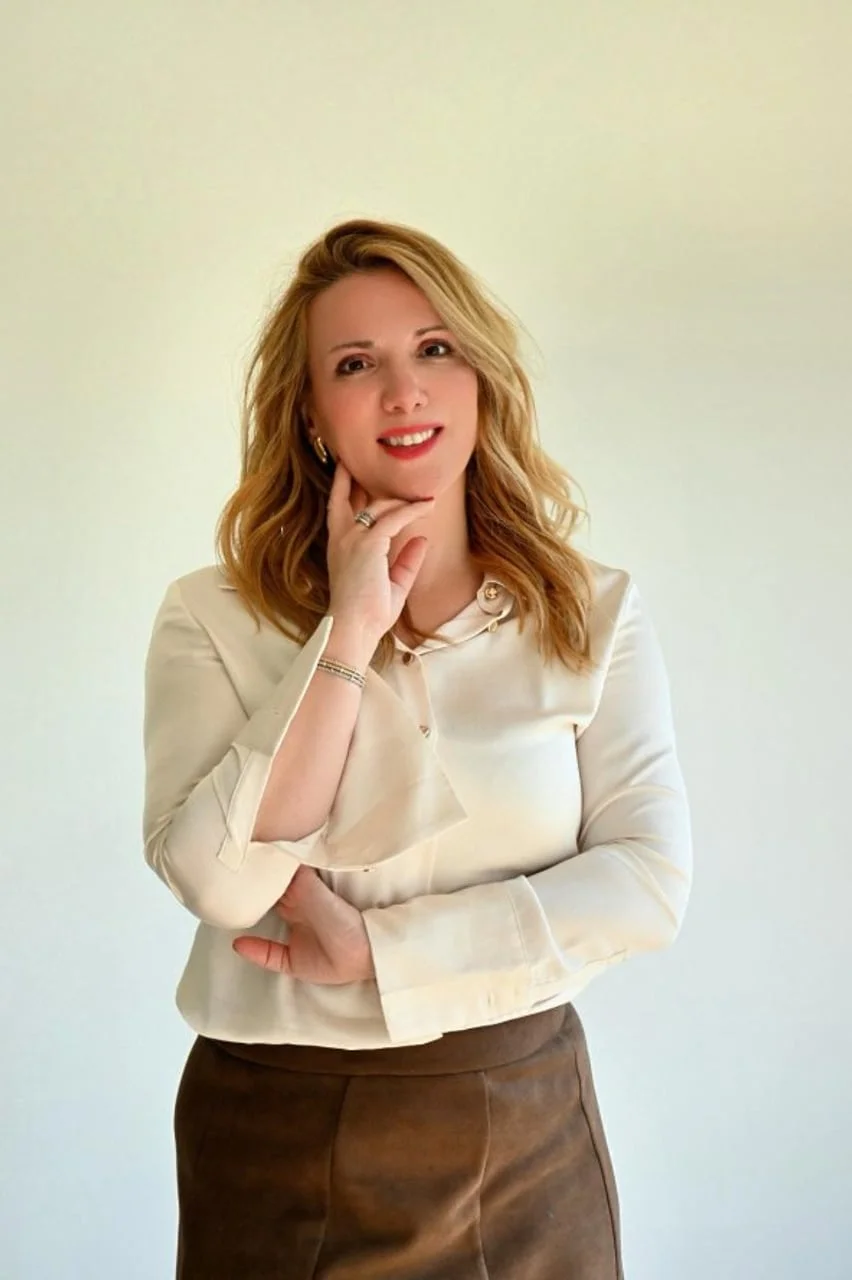 Portret nasmijane žene plavokose u bijeloj bluzi