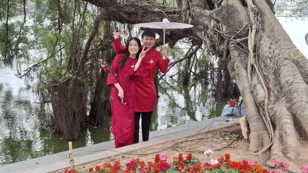 Par u tradicionalnoj crvenoj odjeći pozira pokraj jezera i starog stabla