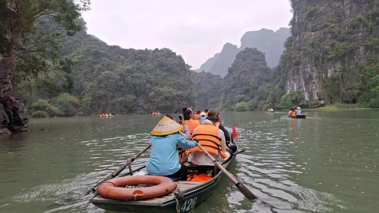 Turisti u čamcima na rijeci okruženoj strmim zelenim brdima